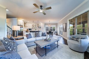 A modern living room with a sectional sofa, a coffee table, and a dining area in the background. - Three Sisters Summit: Mountain Views, Game Room (Black Mountain)