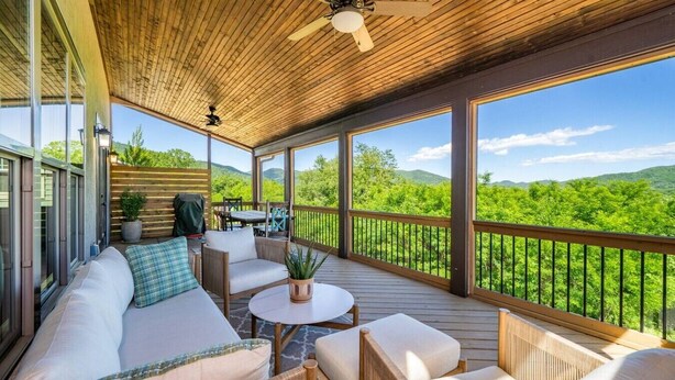 Una terrazza coperta con divano, sedie, tavolo e ventilatore a soffitto.