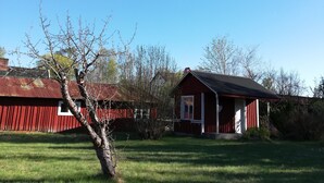 A red barn with a white door and a small attached structure. - The House of Happiness (Boda Glasbruk)
