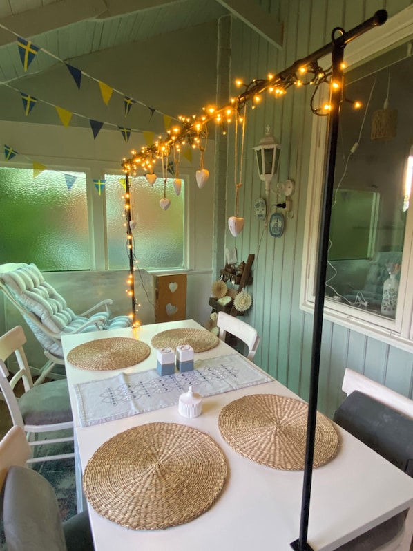 A dining area with a table set for four, featuring woven placemats, candles, and a string of lights.