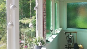 A room with large windows, a small table with a chair, and hanging light fixtures. - The House of Happiness (Boda Glasbruk)