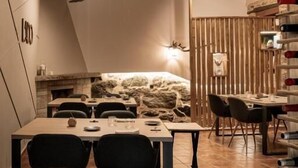 A restaurant with wooden ceiling, stone wall, and a wine rack. - Casa as Fontes (Muíños)