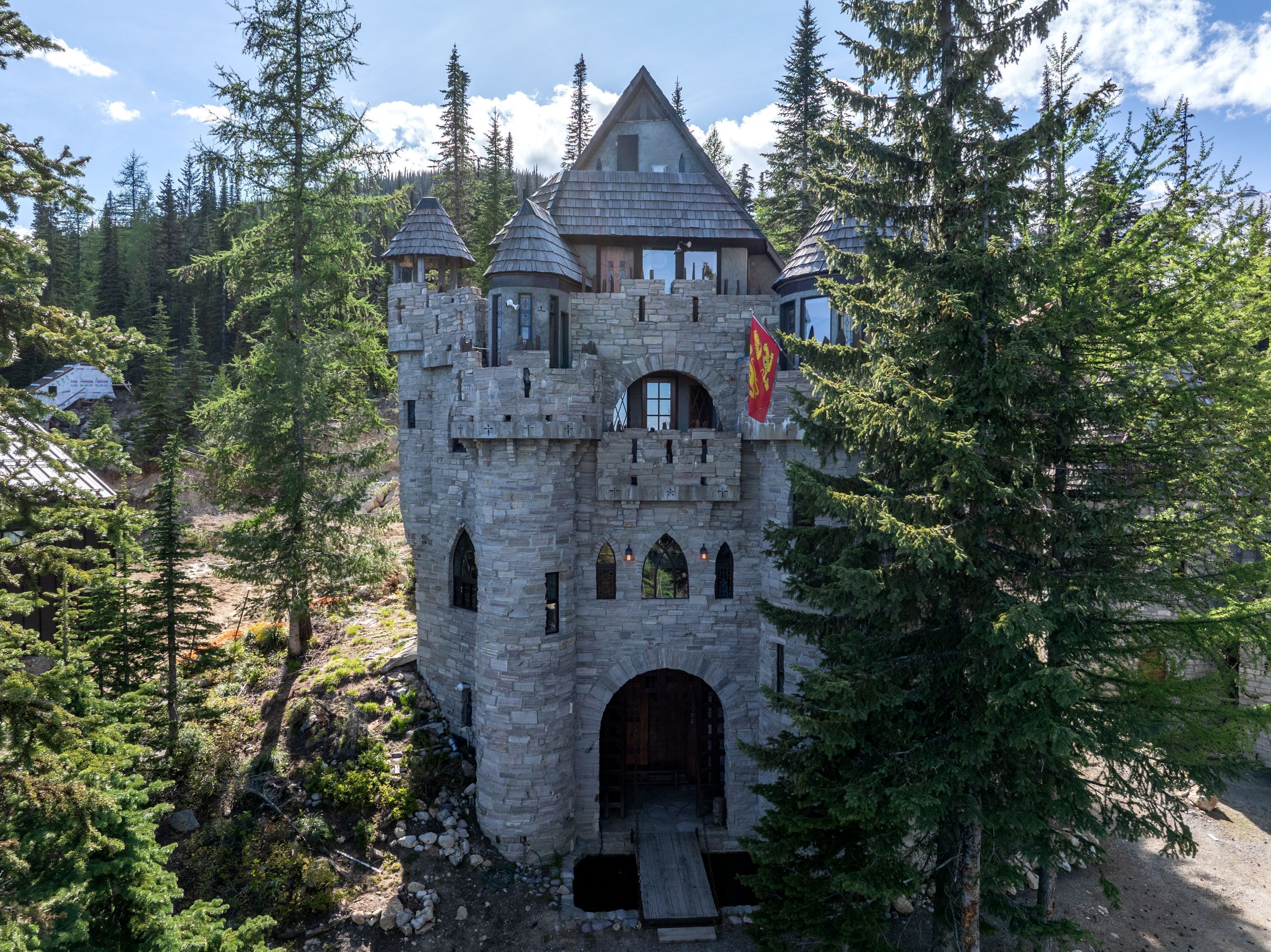Um edifício semelhante a um castelo de pedra, rodeado por árvores.