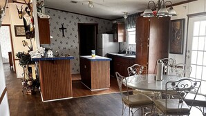 A spacious kitchen with wooden cabinets, a central island, and a dining area with metal chairs.