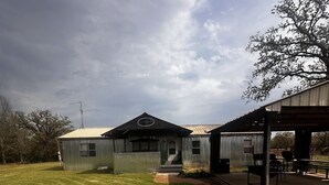 A building with a covered outdoor area, a lawn, and a tree.