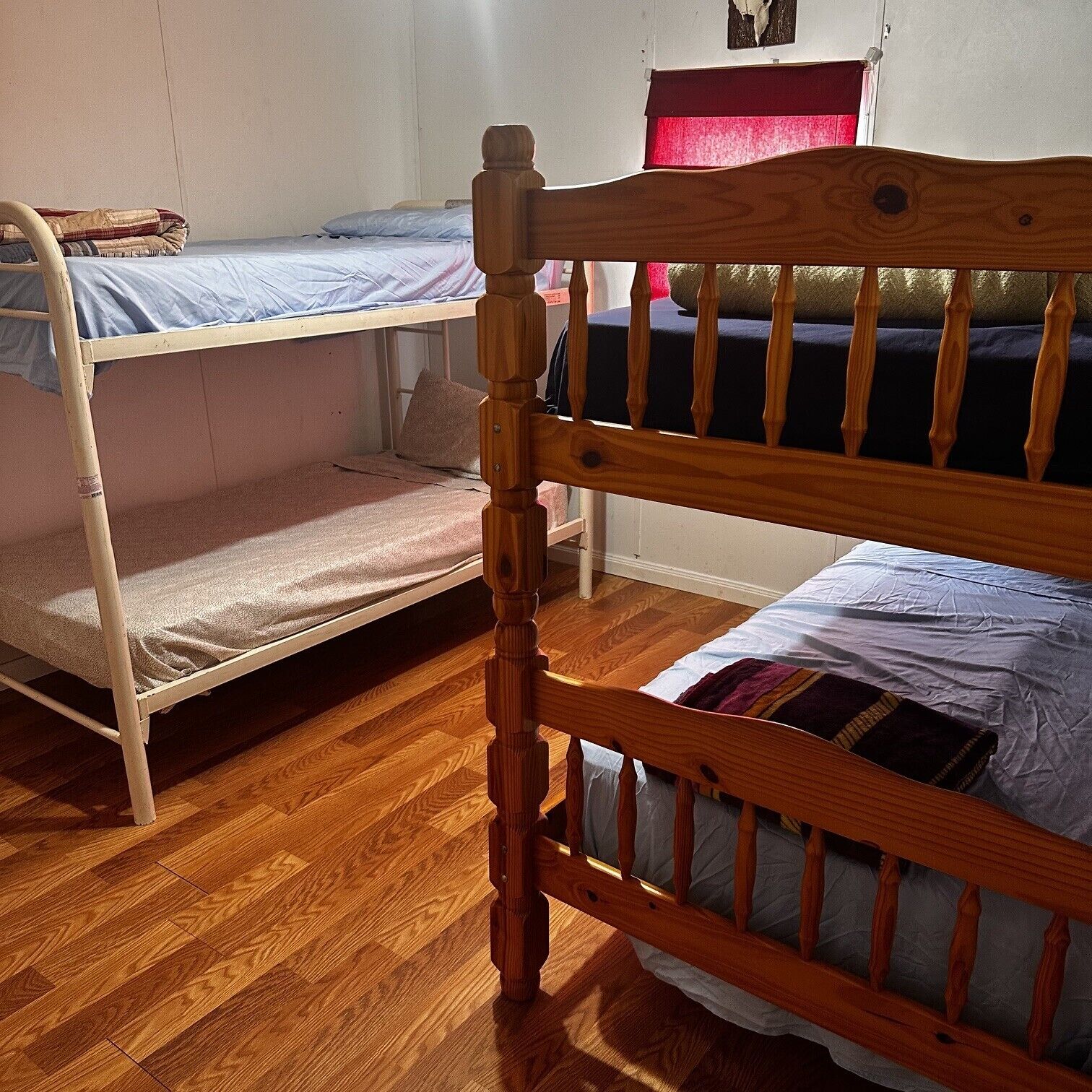 Une chambre avec deux lits superposés, des têtes de lit en bois et un plancher en bois.