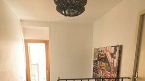 Eine Treppe mit Metallgeländer, eine Nähmaschine auf einem Tisch und ein Gemälde an der Wand.