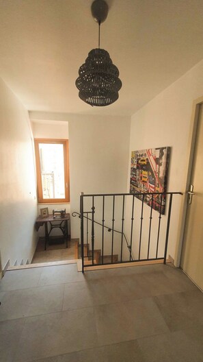 Eine Treppe mit Metallgeländer, eine Nähmaschine auf einem Tisch und ein Gemälde an der Wand.