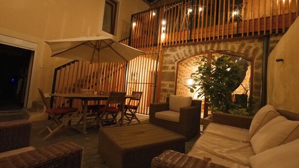 Eine Terrasse im Freien mit Korbmöbeln, einem Tisch und Stühlen sowie einem großen Sonnenschirm.