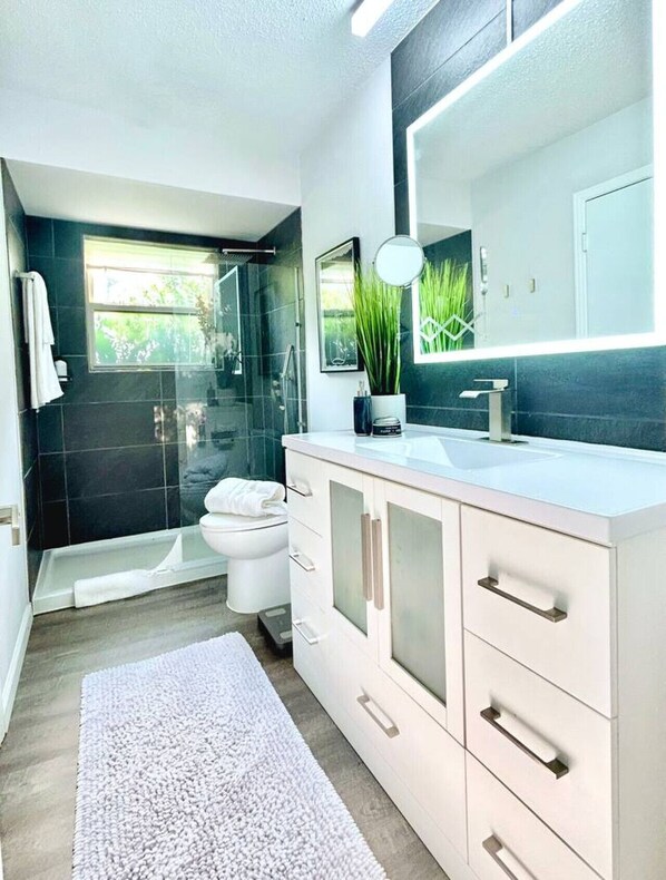 A modern bathroom with a shower, toilet, and sink.
