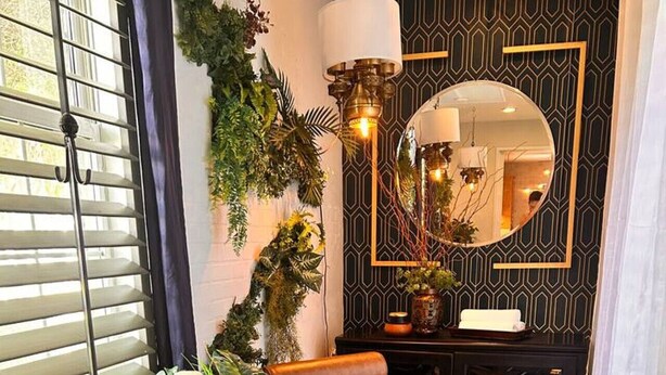 Un fauteuil relaxant avec une table d’appoint, un miroir et une plante en pot.