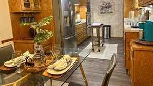 Une cuisine moderne avec des meubles en bois, des appareils en acier inoxydable et un coin repas aménagé pour deux personnes.