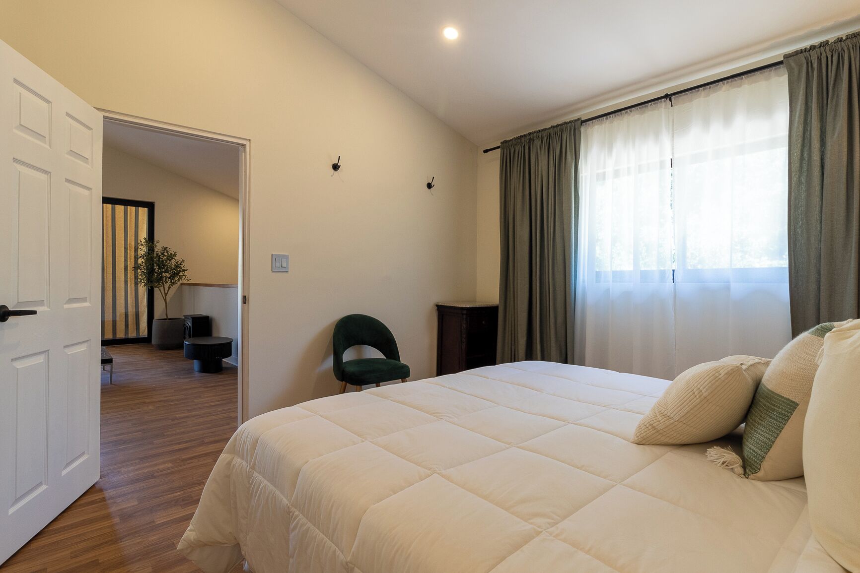 Een slaapkamer met een groot bed, een stoel, een bureau en een plant.
