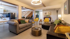 A modern living room with a sofa, armchairs, a coffee table, and a staircase leading to another level. - Casa Bugambilias by Villa de La Rosa (Valle de Guadalupe)
