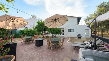Une terrasse extérieure avec des carreaux hexagonaux, plusieurs tables et chaises, et de grands parasols pour créer de l’ombre.