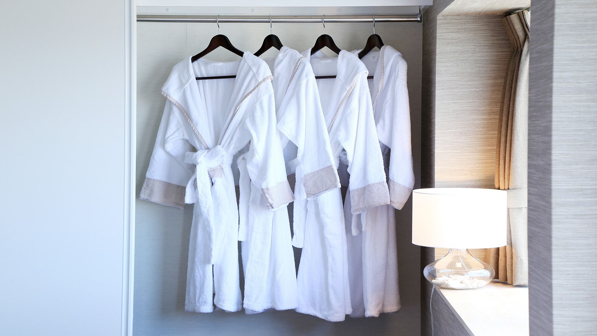 Quarto de hotel com um armário contendo roupões brancos pendurados.