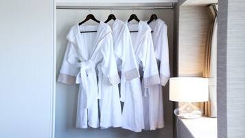 Quarto de hotel com um armário contendo roupões brancos pendurados.