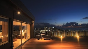 A rooftop terrace with a view of the city skyline at dusk. - Grand Villa Cucule Ishigaki Island (Ishigaki)