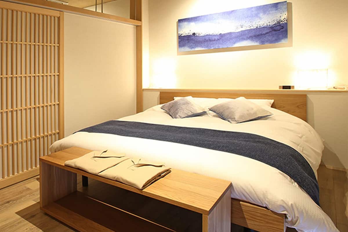 A neatly arranged bedroom with a bed, bedside table, and a wall-mounted artwork.