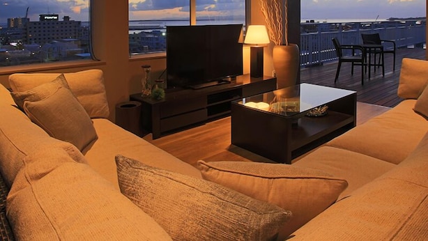 A modern living room with a sofa, TV, and a glass coffee table. - Grand Villa Cucule Ishigaki Island (Ishigaki)