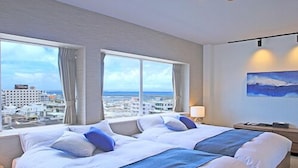 A hotel room with a large bed, two windows, a painting, and a city view. - Grand Villa Cucule Ishigaki Island (Ishigaki)