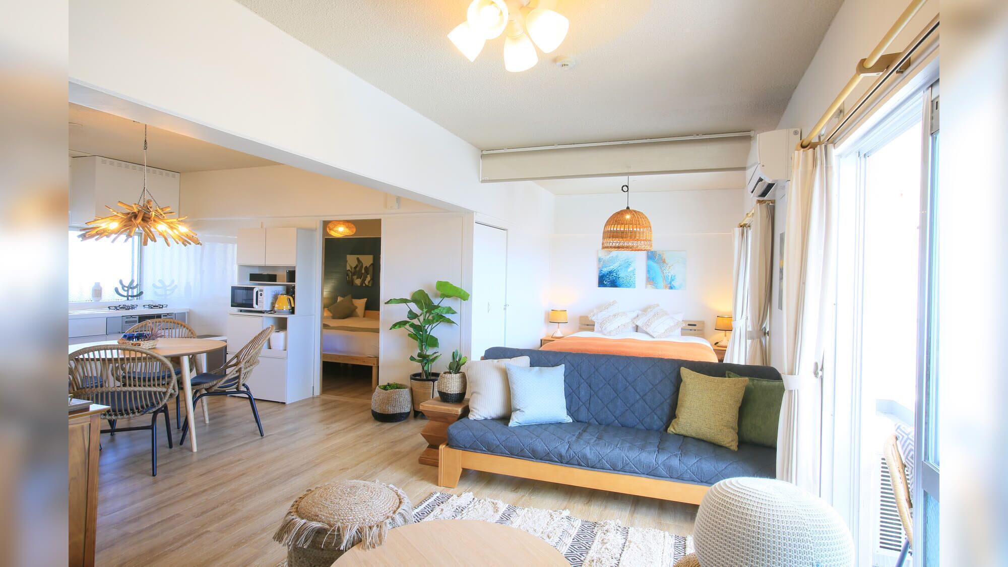 A compact, well-lit room with a bed, seating area, kitchenette, and a dining table.