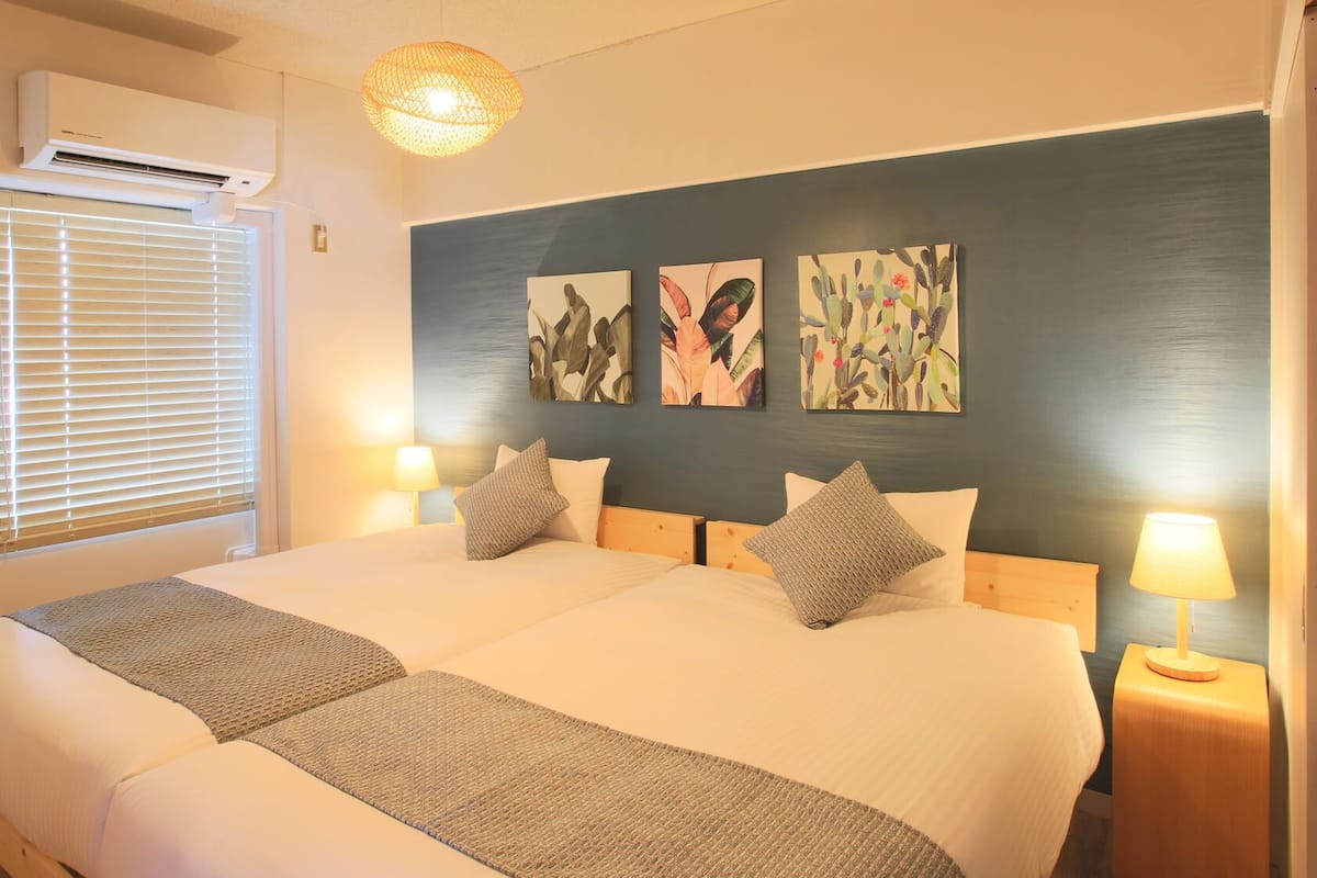 A double bed with a headboard, two bedside lamps, and three wall art pieces.