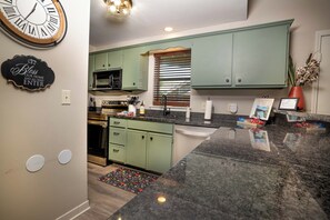 A kitchen with green cabinets, a microwave, a stove, and a sink. - 3 Bedroom, 3 Bath Spacious End Unit Condo on Lake Taneycomo in Pointe Royale (Branson)