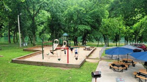 Un parc amb tobogans, taules de pícnic i una zona coberta.