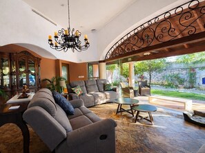 Un amplio salón con un sofá grande, una mesa de centro y una araña.