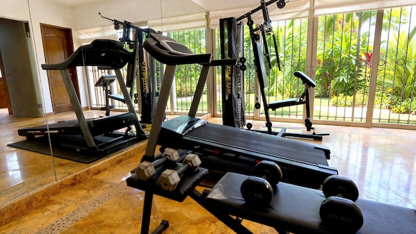 Une salle de sport équipée de machines de cardio, de bancs de musculation et d’haltères.