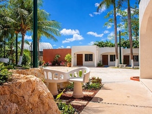 A courtyard with palm trees, a white bench, and a building with arches.