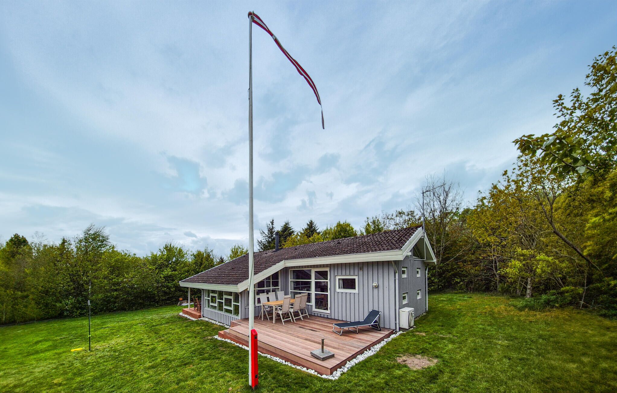 Ett hus med en veranda, en hög stolpe och en gräsig trädgård.