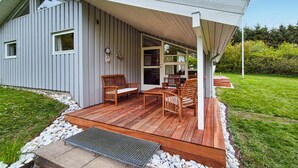 Uma casa moderna com deck de madeira, área de estar externa e varanda coberta.