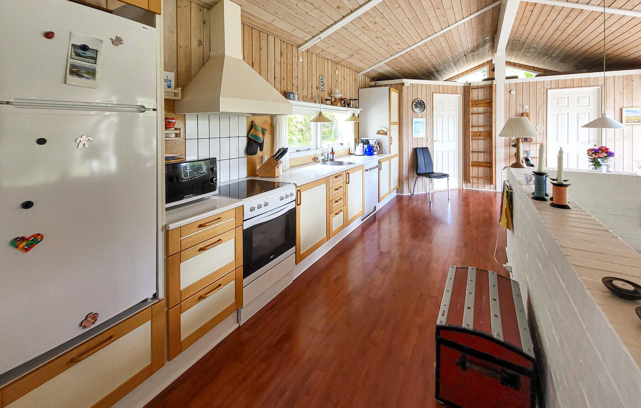 Eine Küche mit Holzschränken, einem Kühlschrank, einem Herd und einer Spüle.