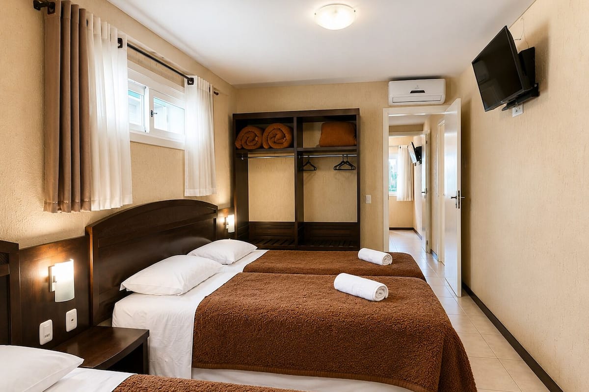 Habitación de hotel con dos camas, un armario, un televisor y un aire acondicionado.