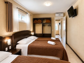 Habitación de hotel con dos camas, un armario, un televisor y un aire acondicionado.