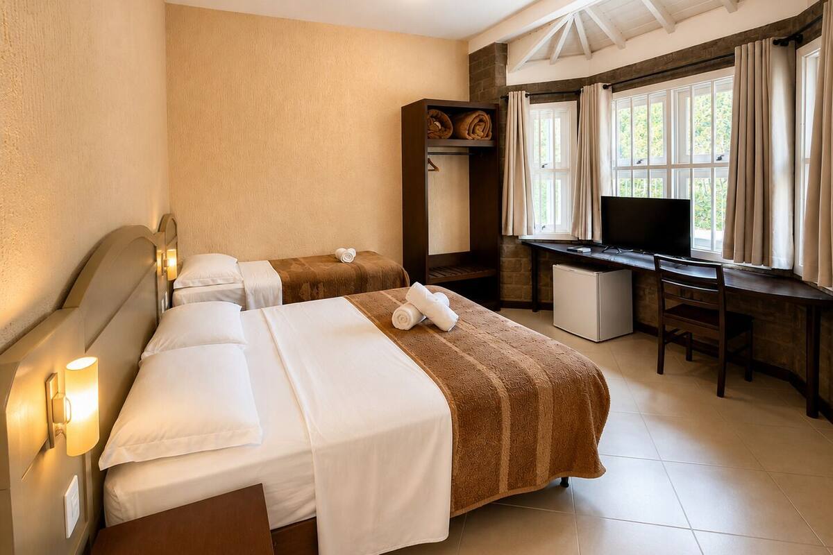 Habitación de hotel con dos camas, un escritorio, un televisor y una ventana con cortinas.