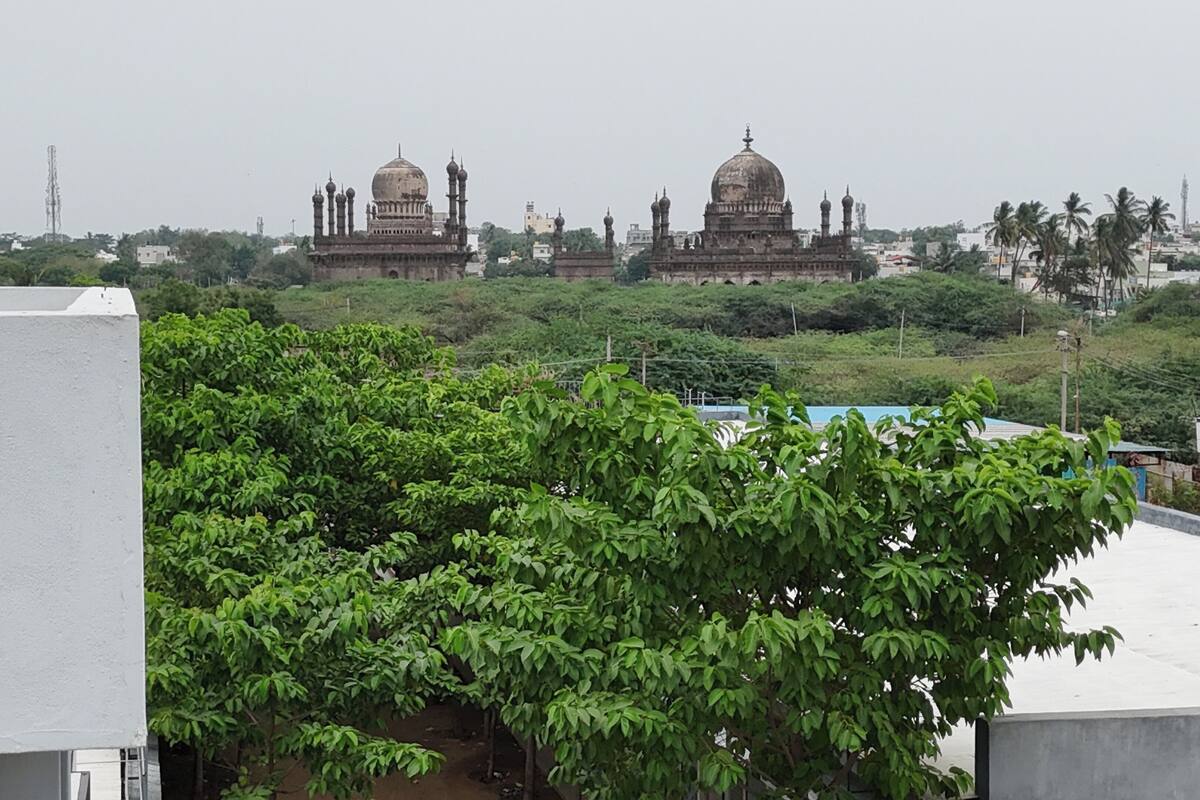 A view of a large historical building with domes and minarets, surrounded by greenery and other buildings.