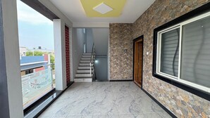 Un couloir avec un escalier, une fenêtre et une porte.