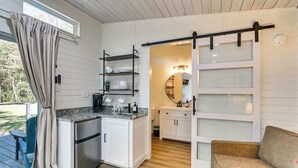 A compact kitchen with a built-in refrigerator, a dining area with a table and chairs, and a sliding glass door leading to a balcony.
