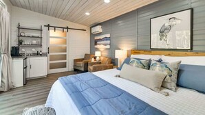 A bedroom with a bed, a desk, a chair, and a wall-mounted shelf.