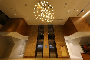 A modern elevator with a brick facade, a circular light fixture on the ceiling, and a fire safety sign on the wall. - Old School (Taichung)