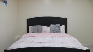 A bed with a black headboard, a floral-patterned bedspread, and two pillows. - Cozy 1-bedroom apartment in perfect Covington with AC (Covington)
