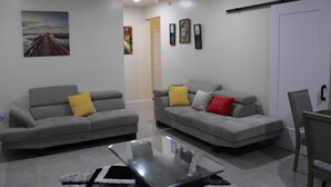 A living room with two grey sofas, a glass coffee table, and a white door. - Cozy 1-bedroom apartment in perfect Covington with AC (Covington)