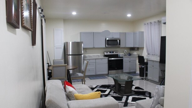A compact living space with a kitchenette, a dining area with a glass table, and a sofa with a throw pillow. - Cozy 1-bedroom apartment in perfect Covington with AC (Covington)