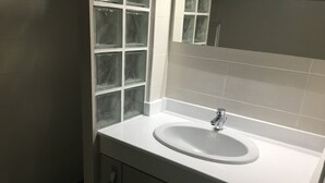 Ein Badezimmer mit einem weißen Waschbecken, einem Spiegel und einem Fenster mit Milchglas.