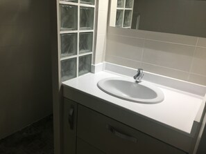 Ein Badezimmer mit einem weißen Waschbecken, einem Spiegel und einem Fenster mit Milchglas.