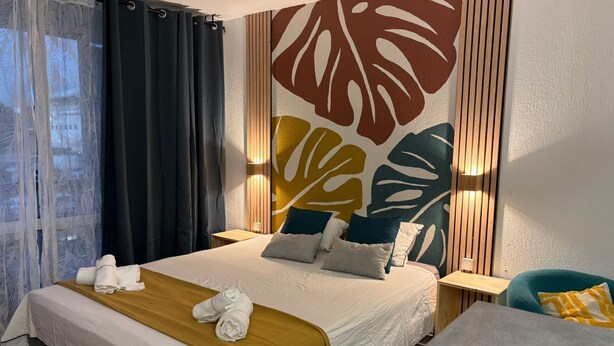 Ein Hotelzimmer mit einem Bett, einem Nachttisch, einem Sessel und einer großen Wandmalerei.