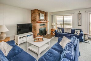 Ein Wohnzimmer mit Kamin, Fernseher, Sofa und einem Balkon mit Blick.